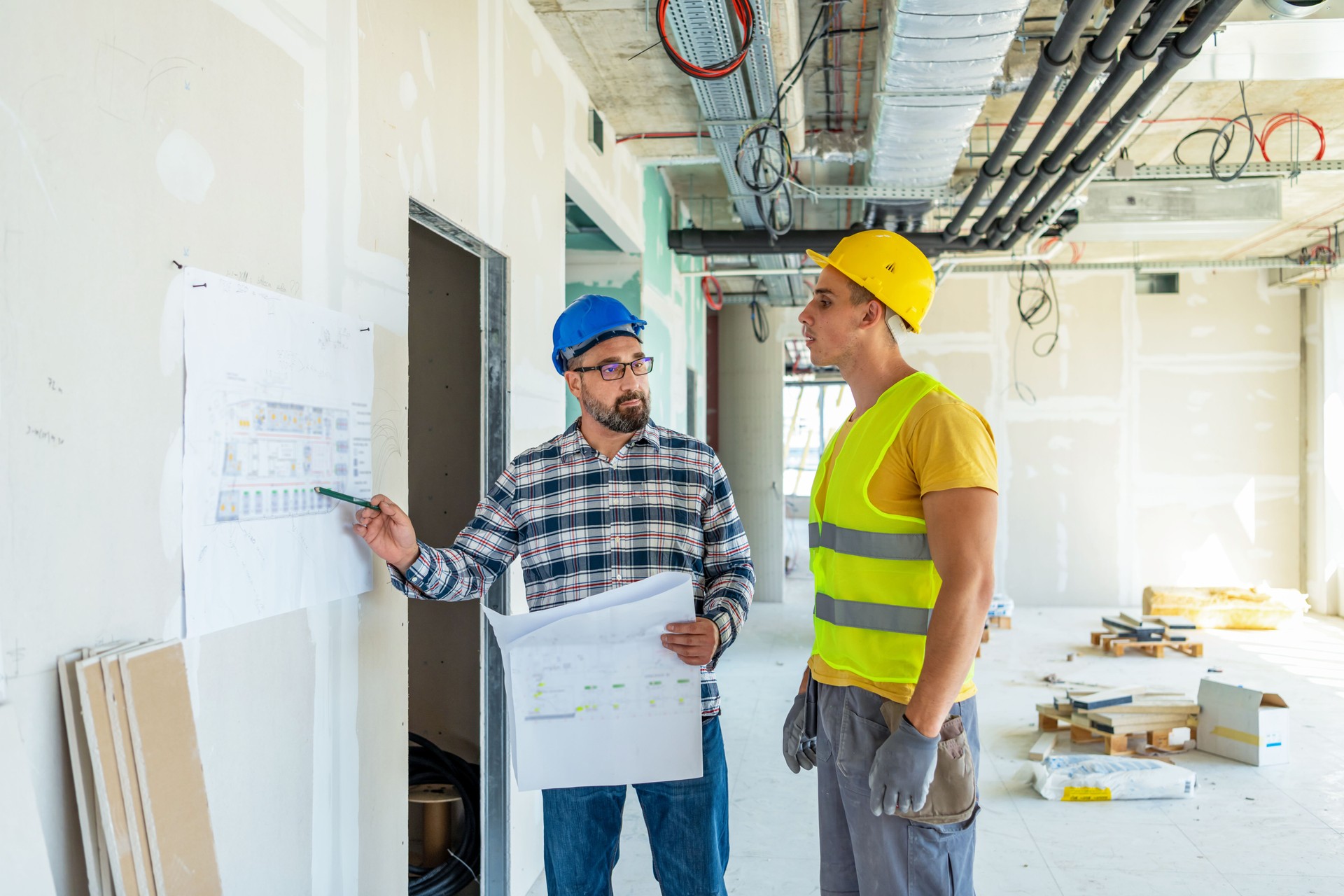 Foreman builder and construction worker with blueprint in indoor apartment