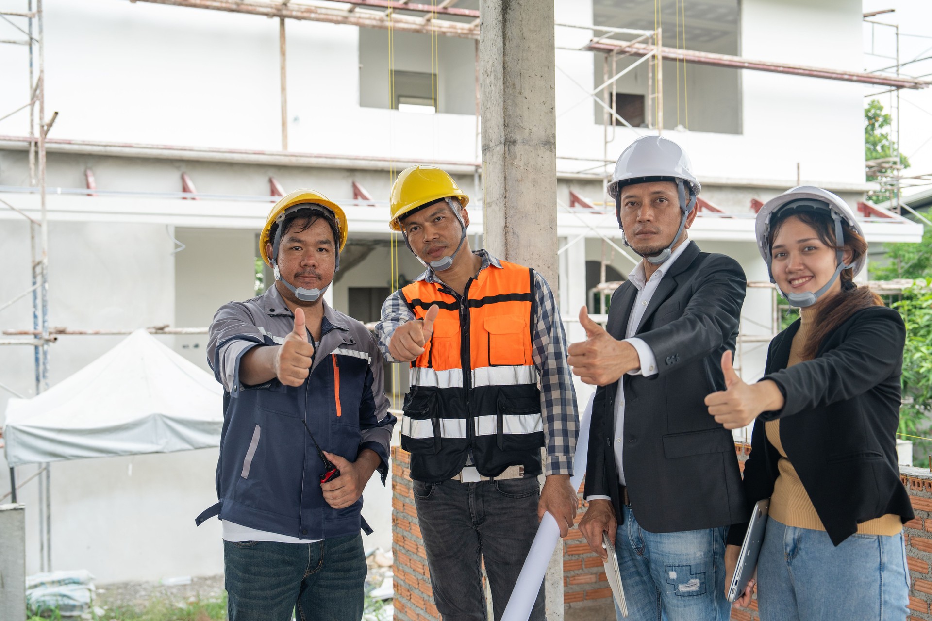 Construction teamwork, Engineer building, Civil Engineer, Contractor and Architect standing with  thumbs up, ware hard hat, construction plan blueprint in construction site.